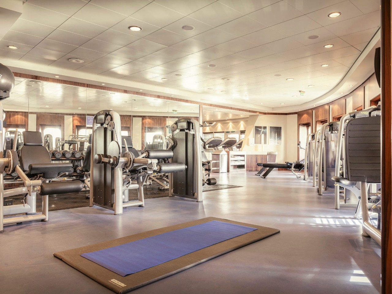 Gym and fitness centre on Queen Mary 2, showing exercise machines and mats, with sea views