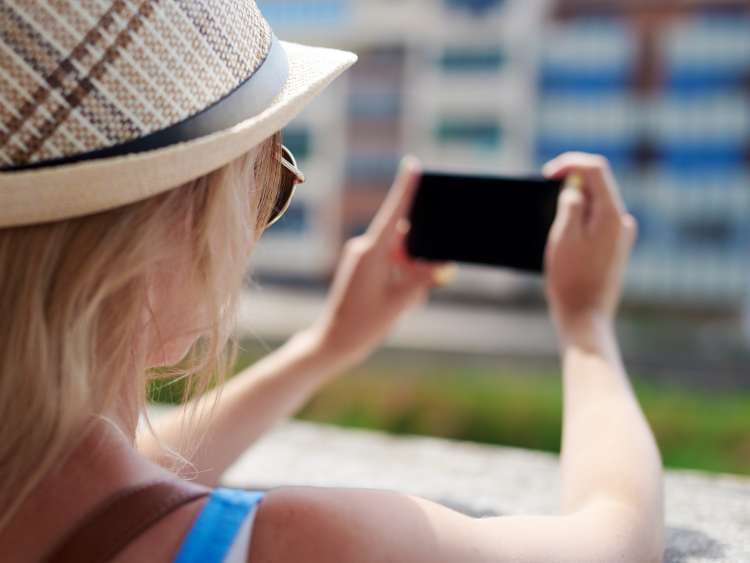 Caucasian female traveler is taking a photo from a river embankment. Back view.; Shutterstock ID 767648197; Invoice Number: -