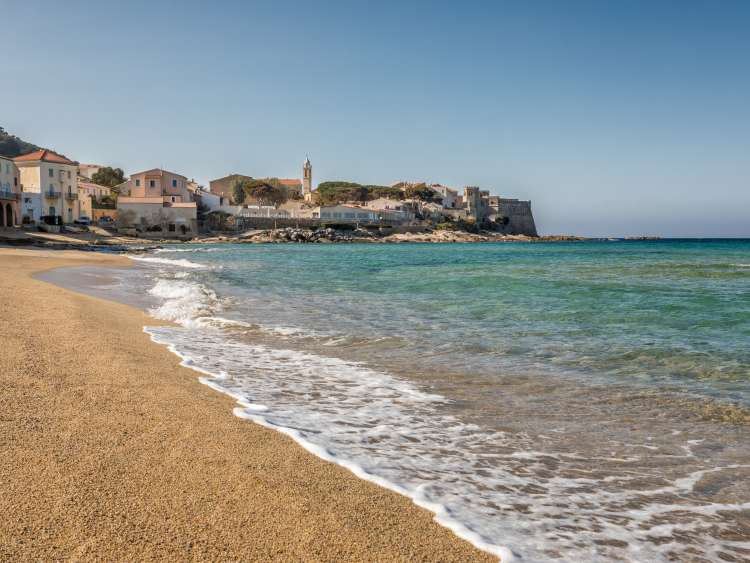 Turqouise Mediterranean sea lapping gently onto the golden sandy beach in front of the Balagne village of Algajola in Corsica; Shutterstock ID 582271594; Invoice Number: -