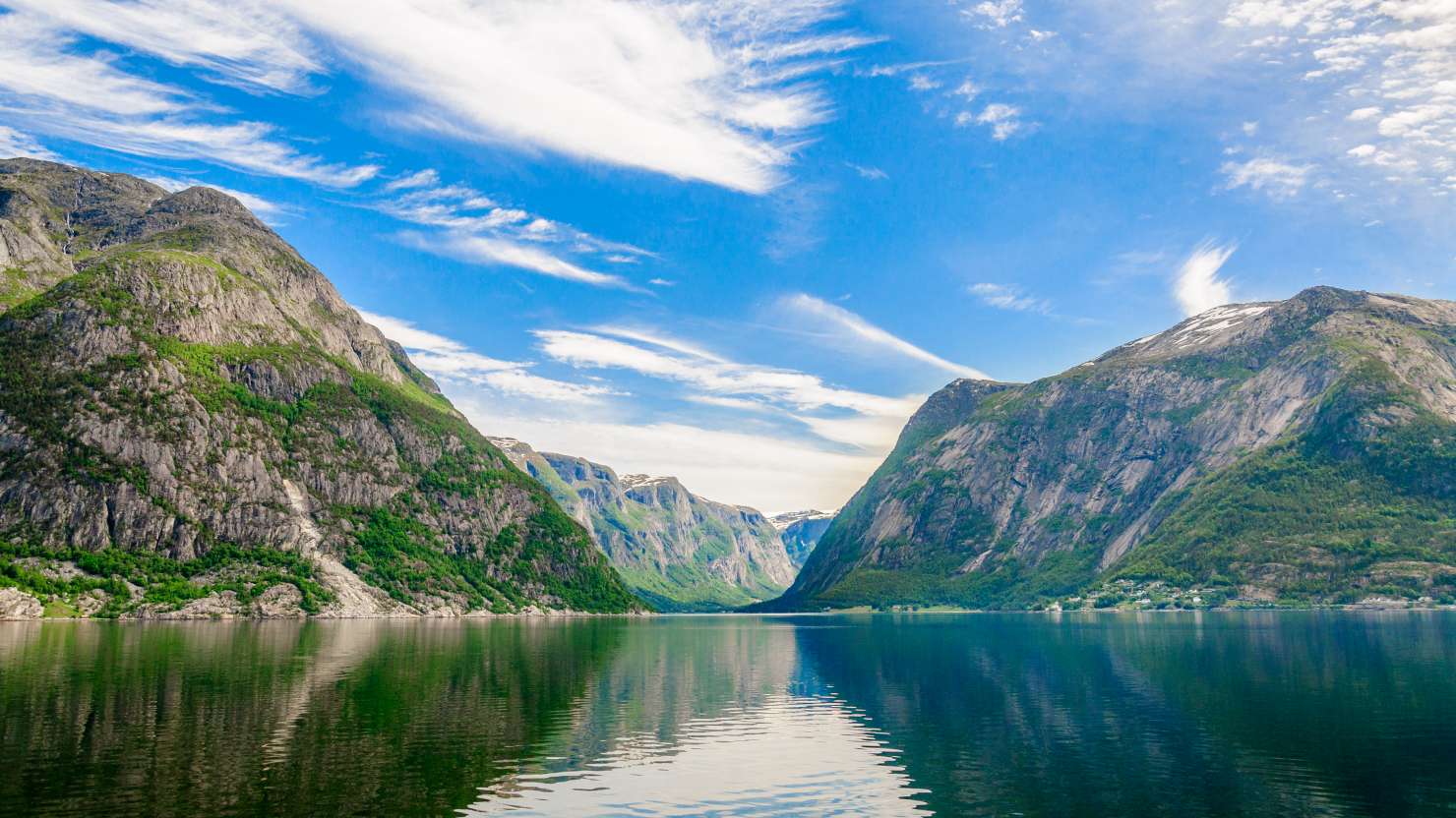 Hardangerfjord's mountain peaks and green slopes with mirror-like water..