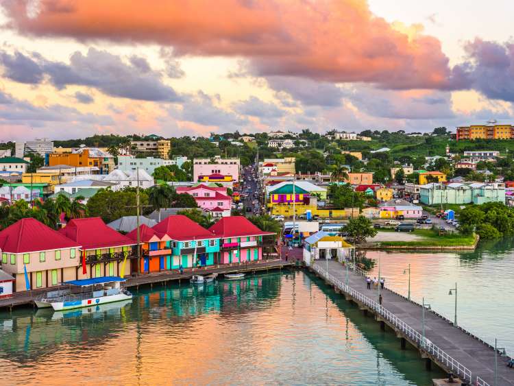 Brightly-coloured houses line the shore at sunset in St. John's, Antigua