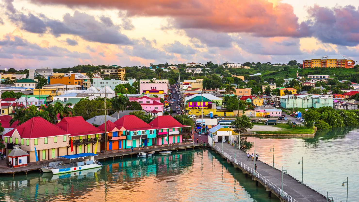 Brightly-coloured houses line the shore at sunset in St. John's, Antigua