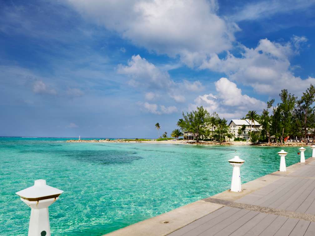 Clear water, palm trees and boardwalk in Grand Cayman, Cayman Islands