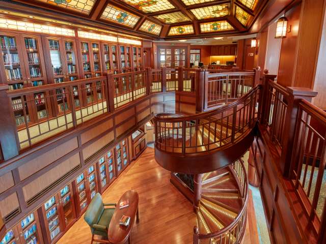 The dual level library on Queen Victoria, with seating areas, floor-to-ceiling bookshelves and a beautiful spiral staircase.