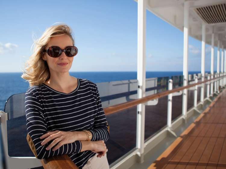 A woman leans against the rail on Queen Victoria's promenade deck