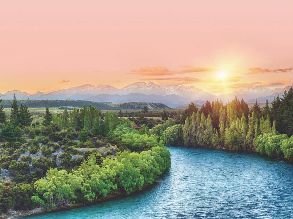 Beautiful sunset over the bend of the river Clutha with Southern Alps peaks on the horizon, New Zealand