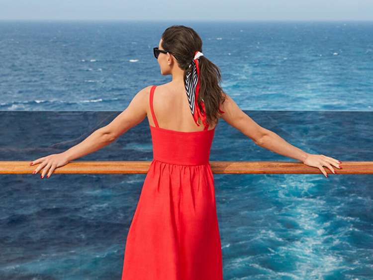 Woman in red dress looking out to sea