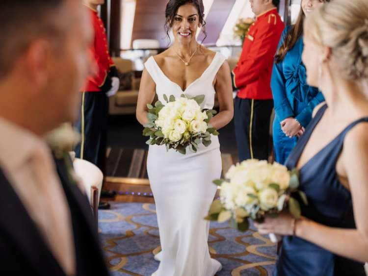 Bride walking into room holding flowers during a wedding ceremony on board a Cunard cruise ship