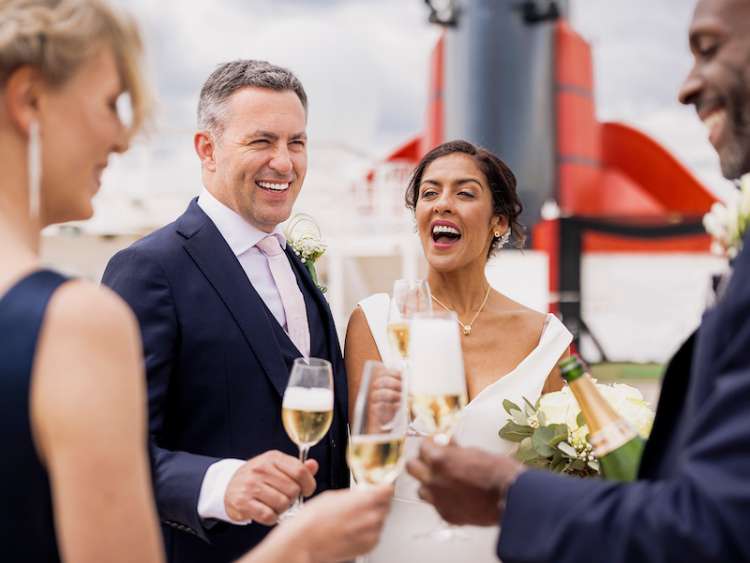 A bride and groom enjoy a glass of champagne on the deck of a Cunard cruise ship