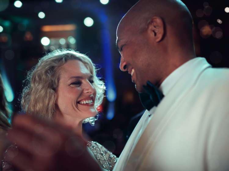 A man in a white tuxedo dancing with a woman during an Ice White Ball gala evening on board a Cunard cruise ship