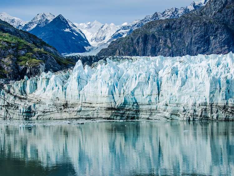 Margerie Glacier in Glacier Bay National Park and Preserve in Southeast Alaska which is twenty-one miles long and one mile wide with layers of rock debris mixed with ice