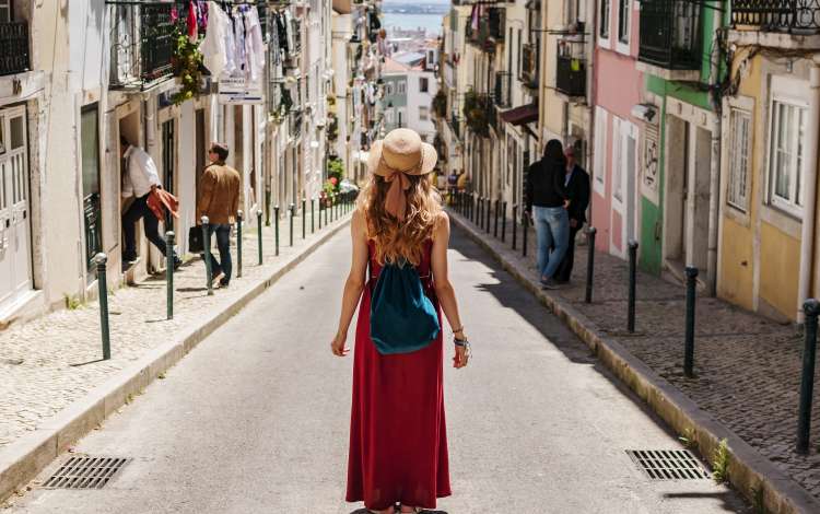 Blonde woman on trip walking by the beautiful southern streets in summer with people in background; Shutterstock ID 737418172; Purchase Order: -