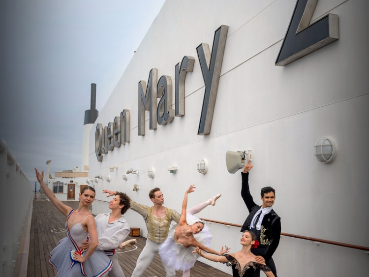 Six ballet dancers in costume pose on deck on Cunard's Queen Mary 2