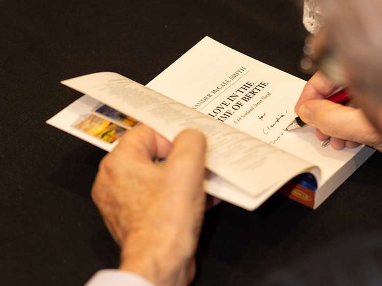 Author Alexander McCall Smith signing a copy of one of his books