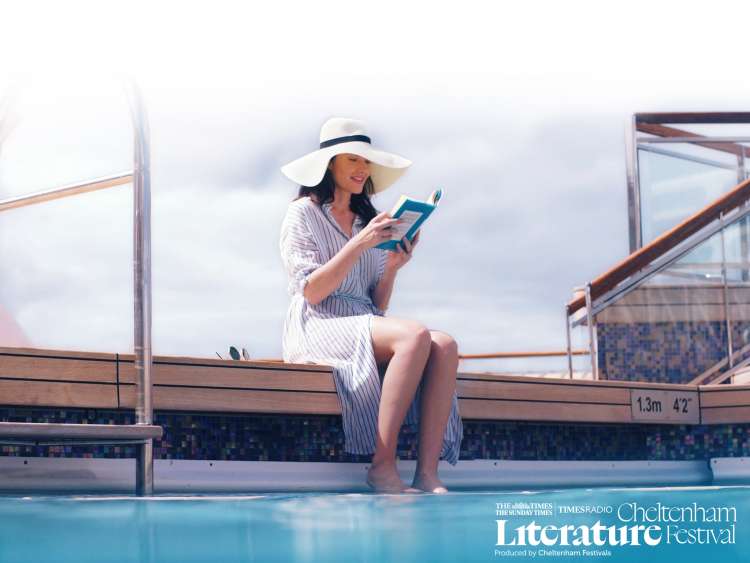 Woman reading a book with her feet in a pool on board a Cunard cruise ship