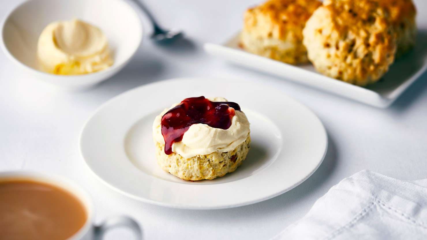 Scone spread with clotted cream and jam at Afternoon Tea