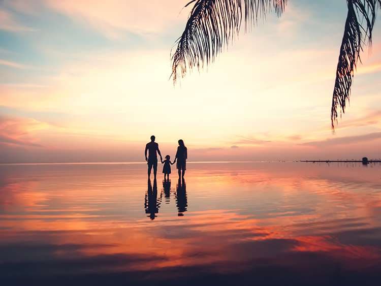 Beautiful sunset landscape with silhouettes of family at the sea