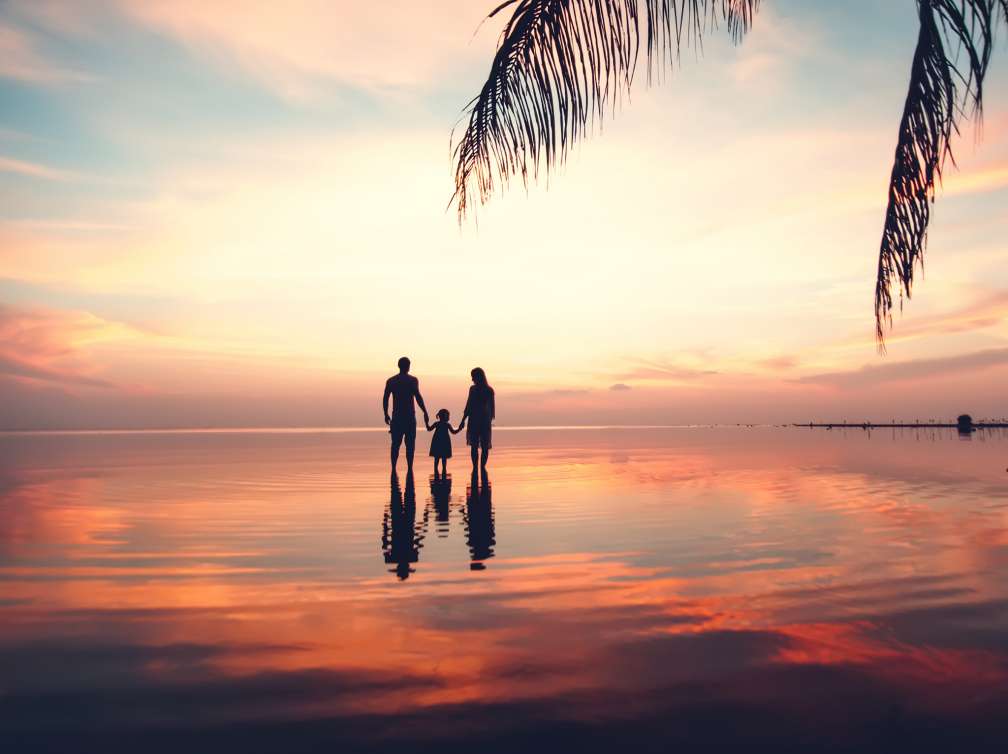 A family silhouetted against sea and sky at sunset