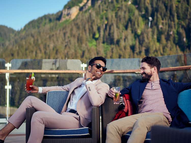 Two men enjoy drinks on the deck of a Cunard cruise ship in Alaska