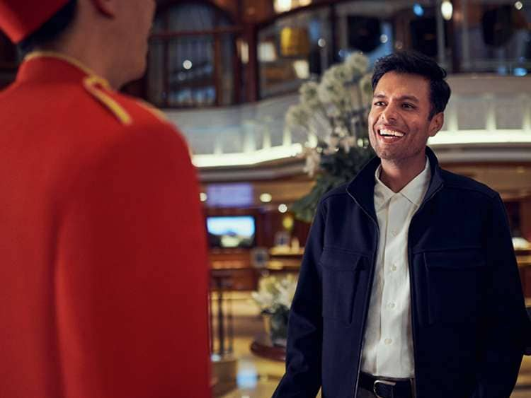 Man welcomed on board by Bellhop in Grand Lobby of Queen Elizabeth