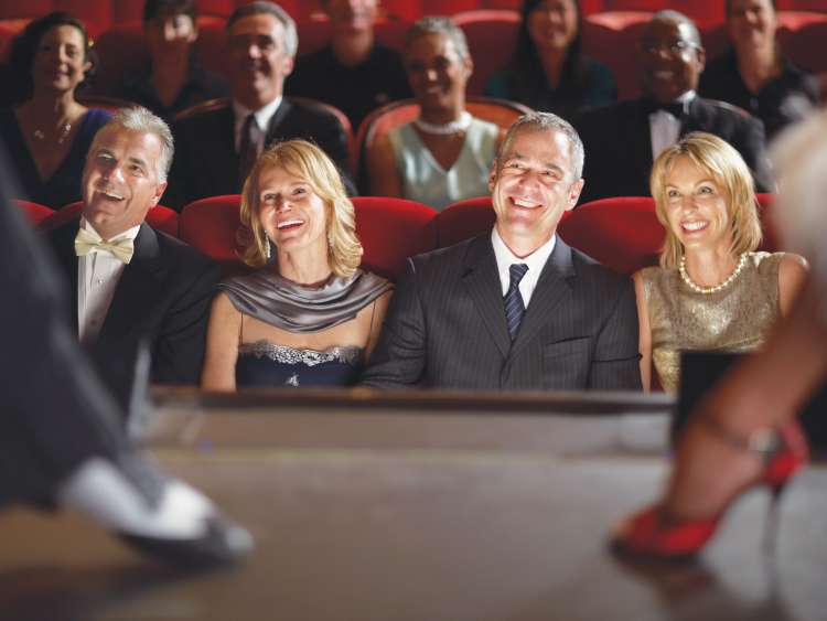 Guests enjoying a show in the Royal Court Theatre on board Cunard's Queen Mary 2.