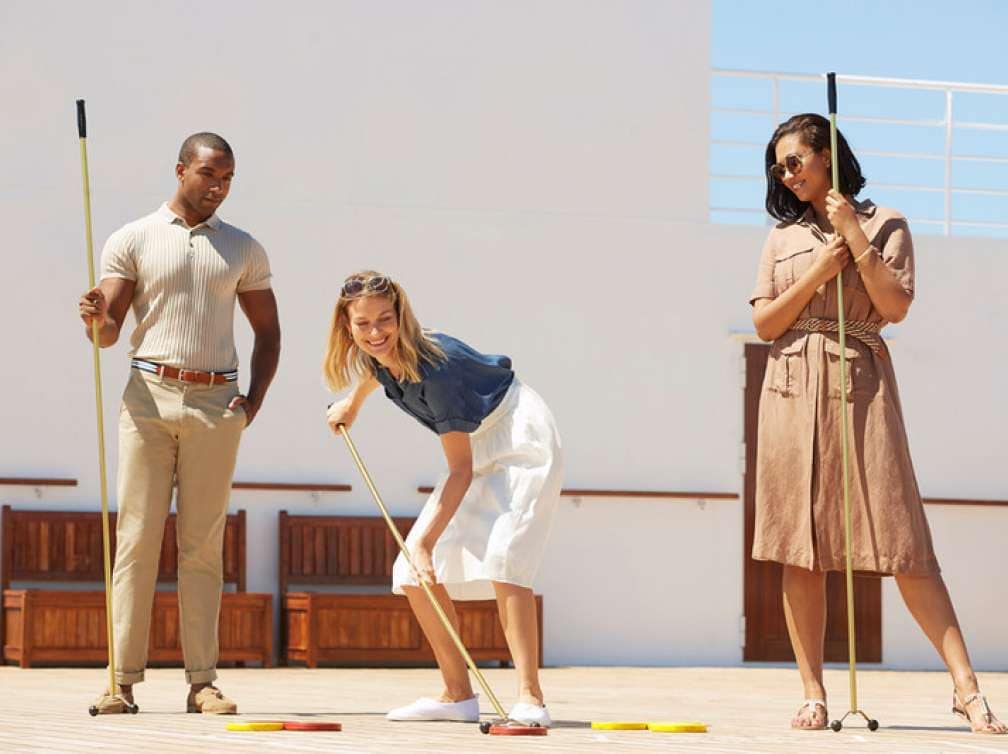 A group of friends play shuffleboard on deck on Queen Mary 2