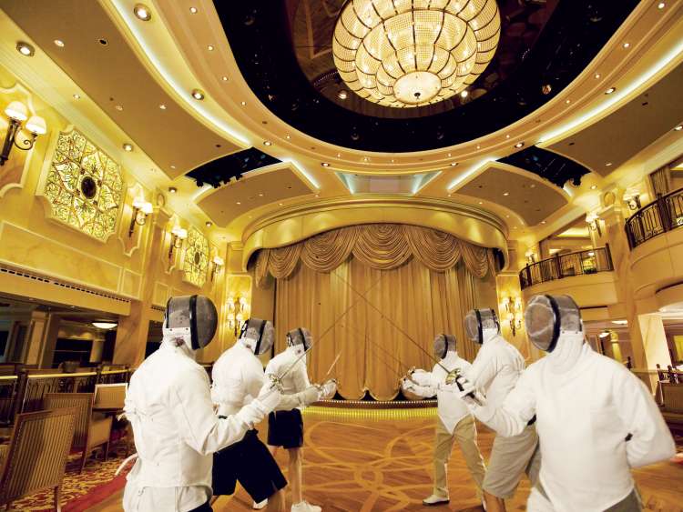 A group of guests in full fencing kit practicing their fencing moves in the Queens Room