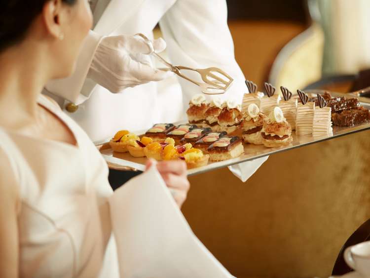 Cakes and pastries offered by white-gloved waiter