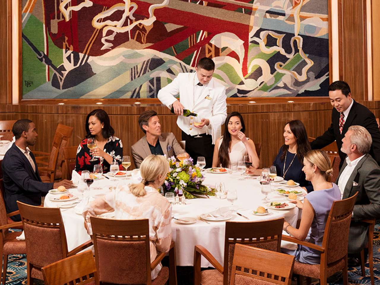 A group of guests dine at the Captain's table in Queen Mary 2's Britannia Restaurant