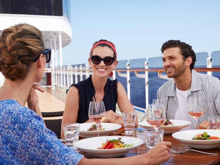 Guests dining outside on the deck of a Cunard cruise ship