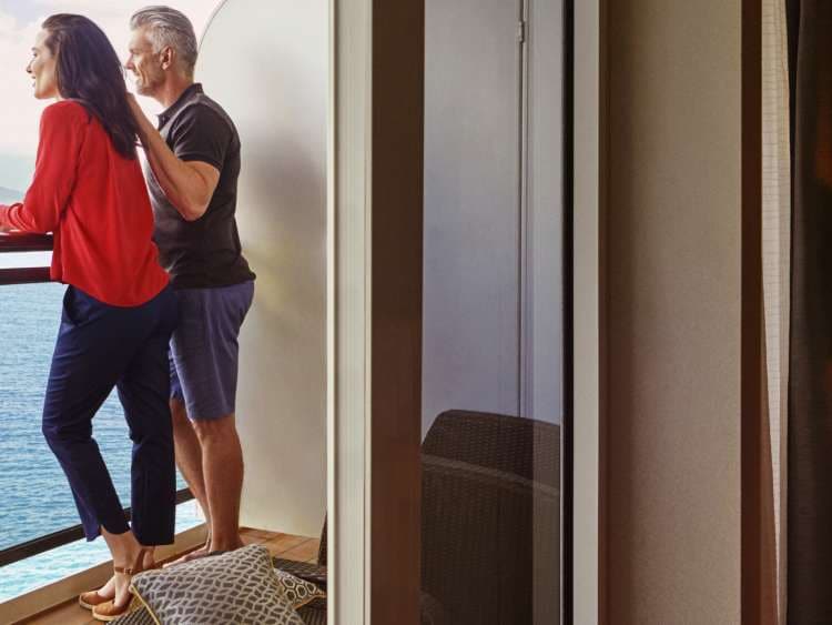 Couple look out from the balcony of their stateroom on board a Cunard cruise ship