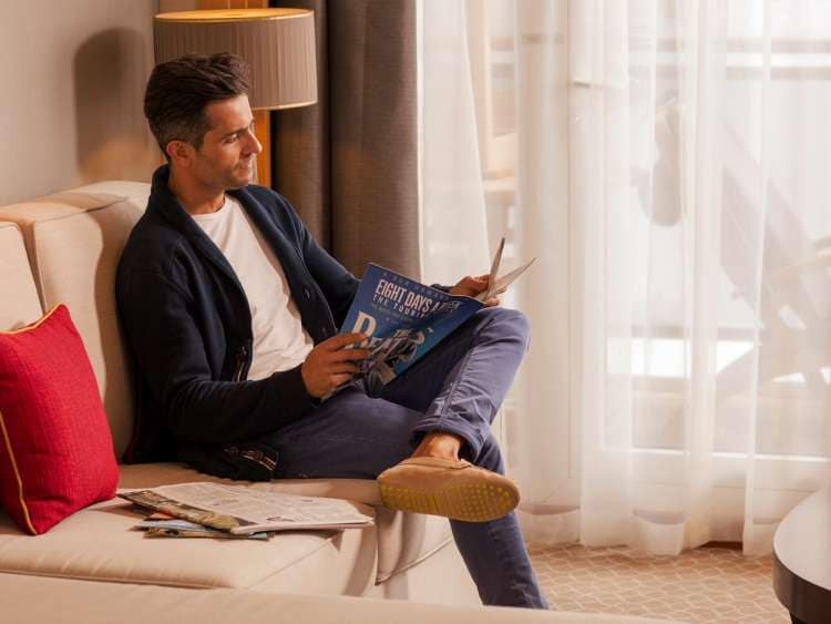 Brand shot of Man relaxing and reading in Queens Suite