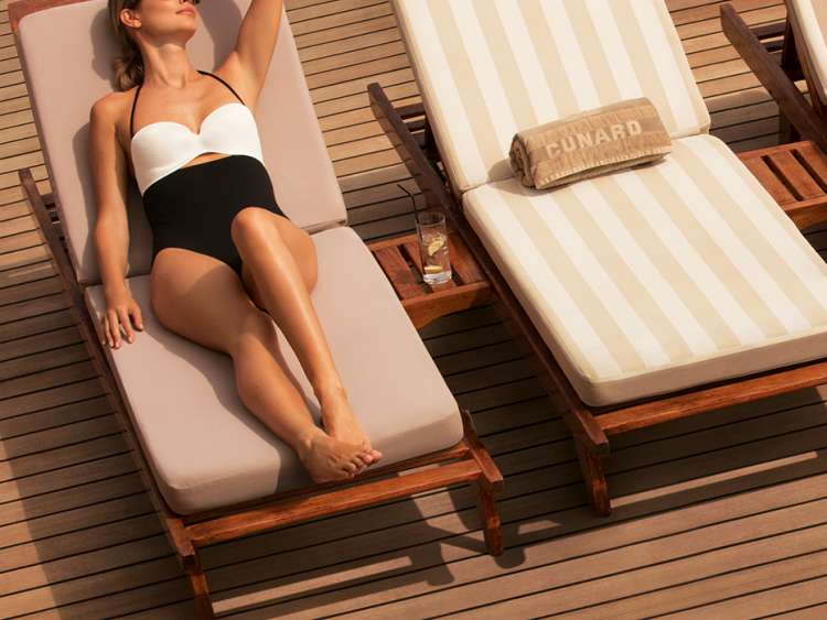 A woman relaxes on a sunbed at Queens Grill Terrace on Queen Mary 2