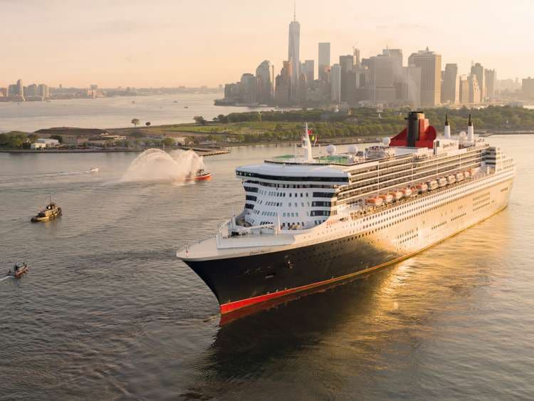 Brand shot of QM2 sailing out of New York at sunset