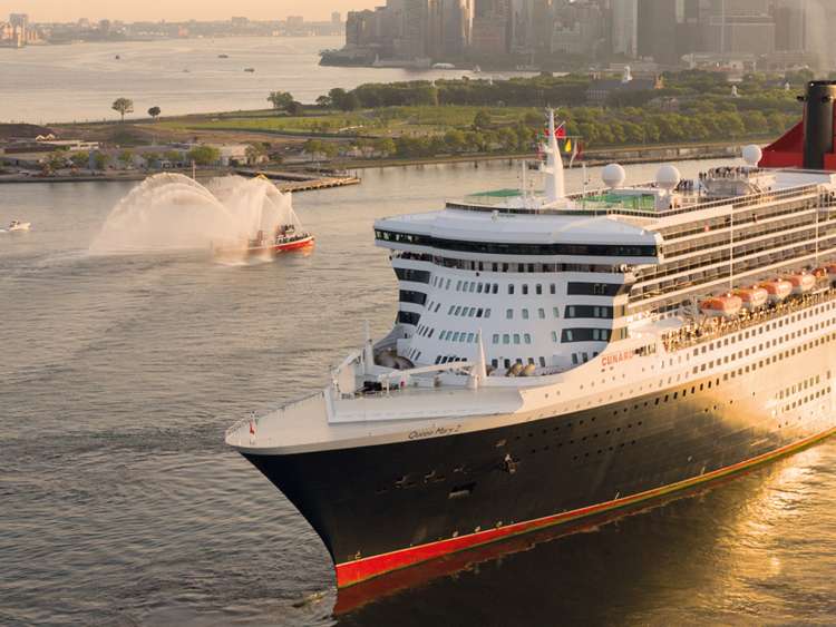 Brand shot of QM2 sailing out of New York at sunset