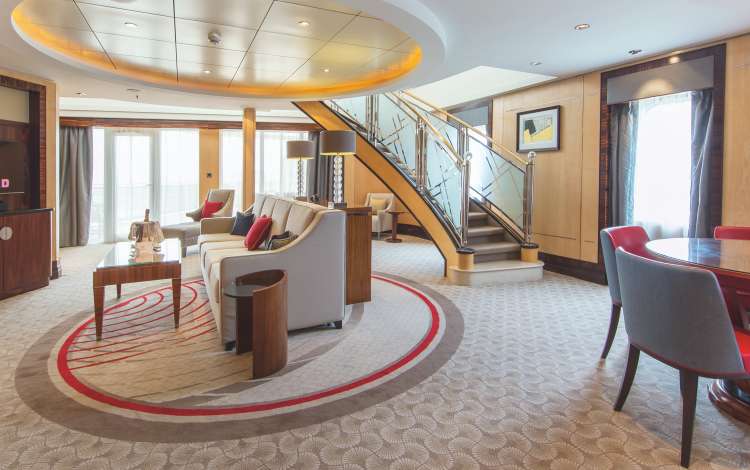 The lower level of the Balmoral Suite on Cunard's flagship, QM2.  A spacious lounge area, with dining table, balcony doors and sweeping staircase, are the centre to one of our most luxurious suites on board.