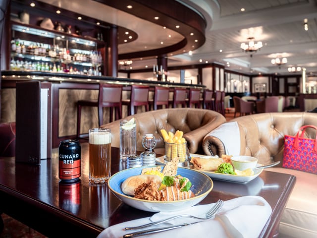 Traditional British pub food and Cunard Red beer on a table in the Golden Lion pub, on board Queen Mary 2