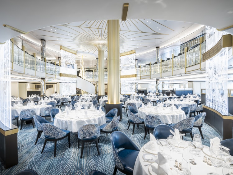 Wide shot of Queen Anne's Britannia restaurant, showing two-deck space with golden columns, tables and chairs