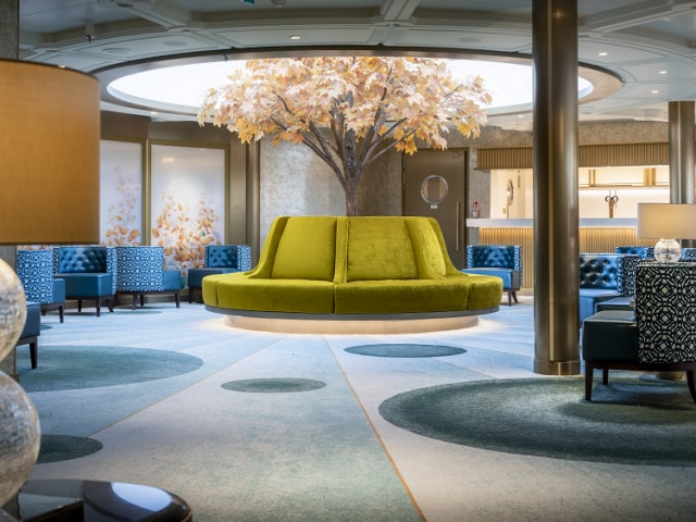 Queen Anne's Grills lounge, with plush seating, circular skylight and autumnal tree centrepiece