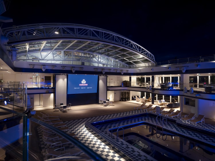 Nighttime view of Queen Anne's Pavilion venue, taken from the upper deck, showing pool, open roof and cinema screen