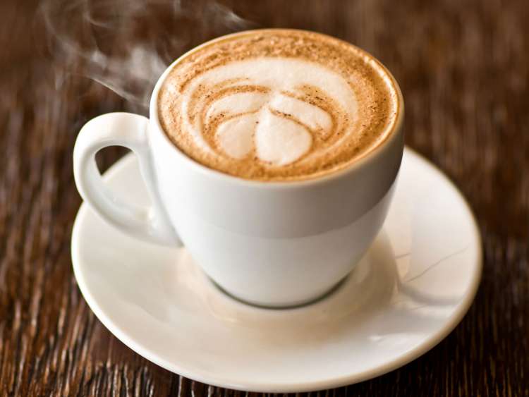 A hot, frothy cup of coffee on a saucer