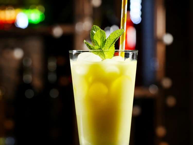 Glass of cocktail in bar on bright blurred background