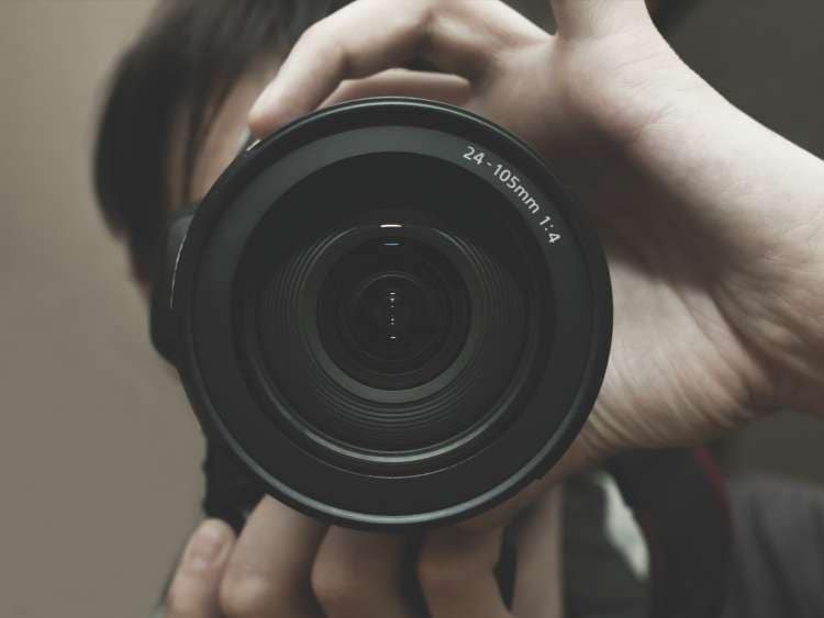 A person looks through a large camera lens